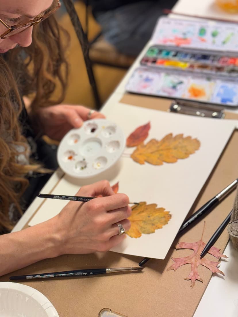 Kvinna långt hår som målar akvarell av ett blad